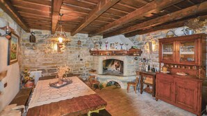 A rustic room with a stone fireplace, wooden beams, and a traditional wooden cabinet.
