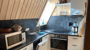 Eine kleine Küche mit Mikrowelle, Backofen, Spüle und Geschirrspüler.
