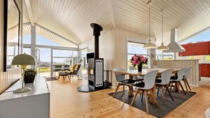 A spacious kitchen with wooden flooring, a central island, and large windows offering views of the outdoors. - Beautiful home in Rønde with sauna (Rønde)