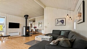 A modern living room with a fireplace, a sofa, a coffee table, and a TV. - Beautiful home in Rønde with sauna (Rønde)