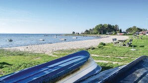 A beach with boats, a sandy shore, and houses in the background. - Beautiful home in Rønde with sauna (Rønde)