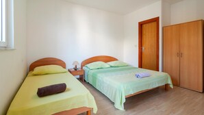 Een slaapkamer met twee enkele bedden, een nachtkastje met een lamp, een garderobe en een raam.