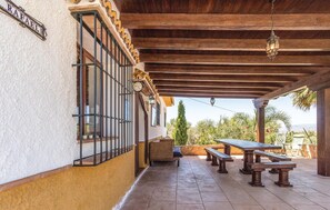 Relax in the serene garden view from this covered patio with a seating area and metal gate.