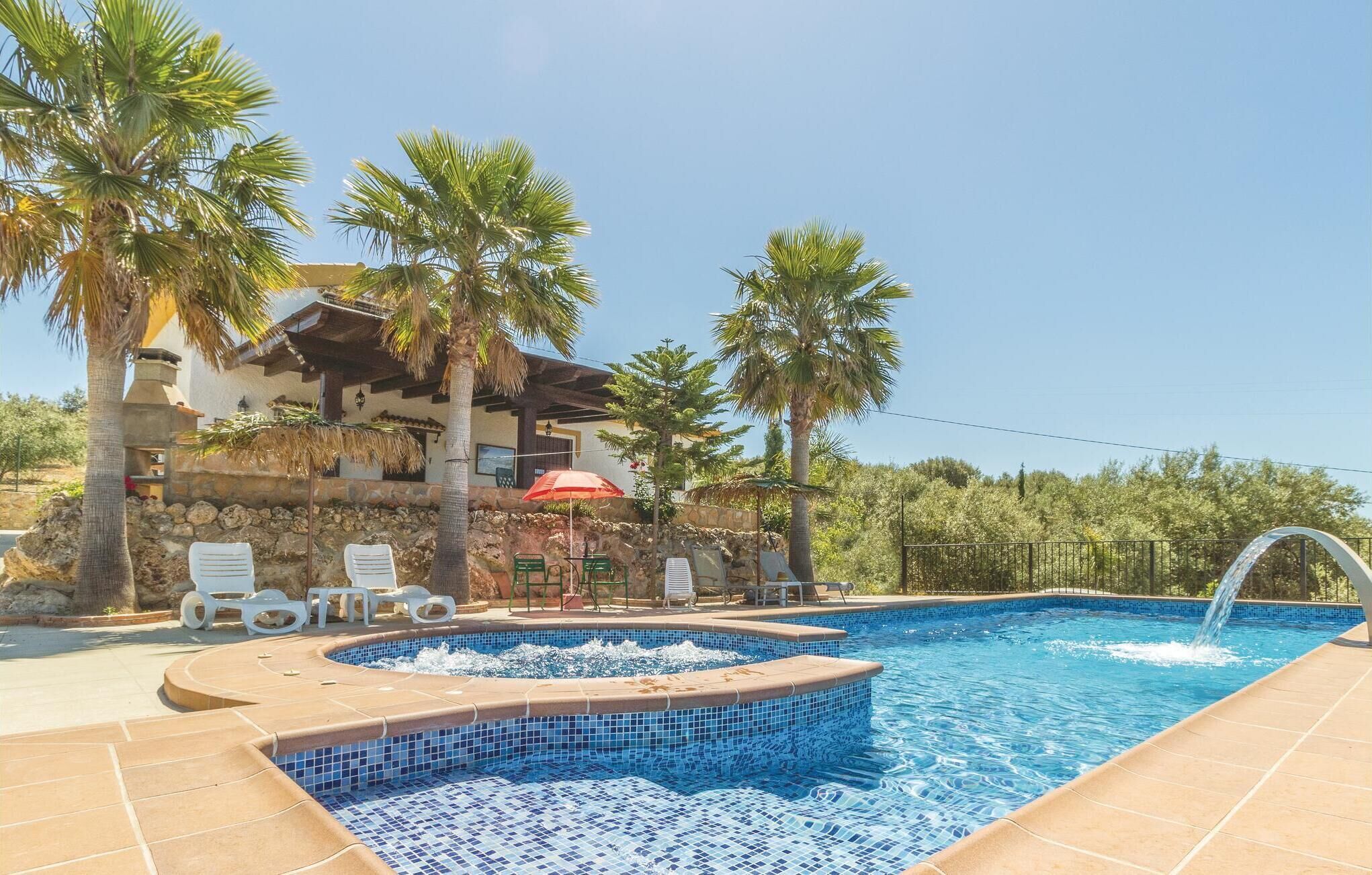 A swimming pool with a tiled edge, lounge chairs, and palm trees.