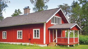 A red wooden house with a sloped roof, a chimney, and a porch. - Cozy home in Katrineholm with lake view (Katrineholm)