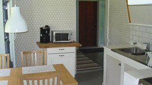 A compact kitchen with a microwave, coffee maker, and a sink. There is a wooden table and chairs, and a patterned wallpaper. - Cozy home in Katrineholm with lake view (Katrineholm)