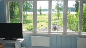 A room with a large window overlooking a grassy area and a body of water. - Cozy home in Katrineholm with lake view (Katrineholm)