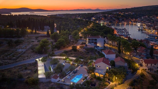 A coastal town at sunset with a marina, a swimming pool, and residential buildings. - Amazing home in Milna (Milna)