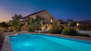 A swimming pool with lounge chairs, a covered patio, and a house with a red roof and a chimney. - Amazing home in Milna (Milna)
