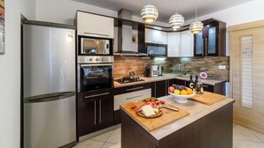A modern kitchen with stainless steel appliances, wooden cabinetry, and pendant lighting. - Amazing home in Milna (Milna)