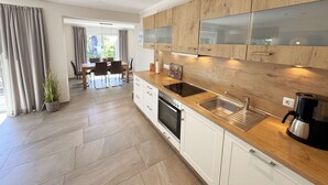 Een moderne keuken met houten kastjes, een inbouwoven en een koffieapparaat.