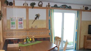 Un comedor con una mesa de madera, sillas, un banco y una pared decorativa con cuadros.