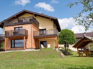 A two-story house with a balcony, a small garden, and a picnic table. - Holiday family happiness - Farm Schöb Ringer Frühstückspension (Miglberg)