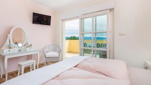 A bedroom with a bed, a vanity with a mirror, a chair, and a balcony with a view. - Amazing home in Lovran with sauna (Lovran)