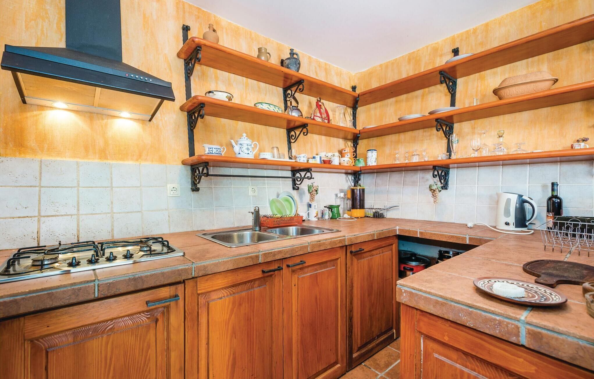 A kitchen with wooden cabinets, a gas stove, a sink, and shelves with kitchenware.