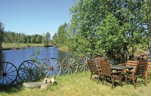 A lakeside picnic area with wooden benches and a table, surrounded by large water wheels and a tree. - Pet friendly home in Skillingaryd (Skillingaryd)