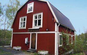 En röd lada med ett sadeltak, en trädörr och en liten veranda med några trappsteg.