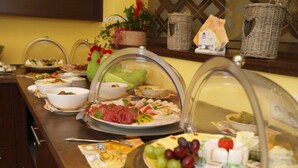 Um buffet com diversos itens de comida, incluindo carnes, queijos e frutas.