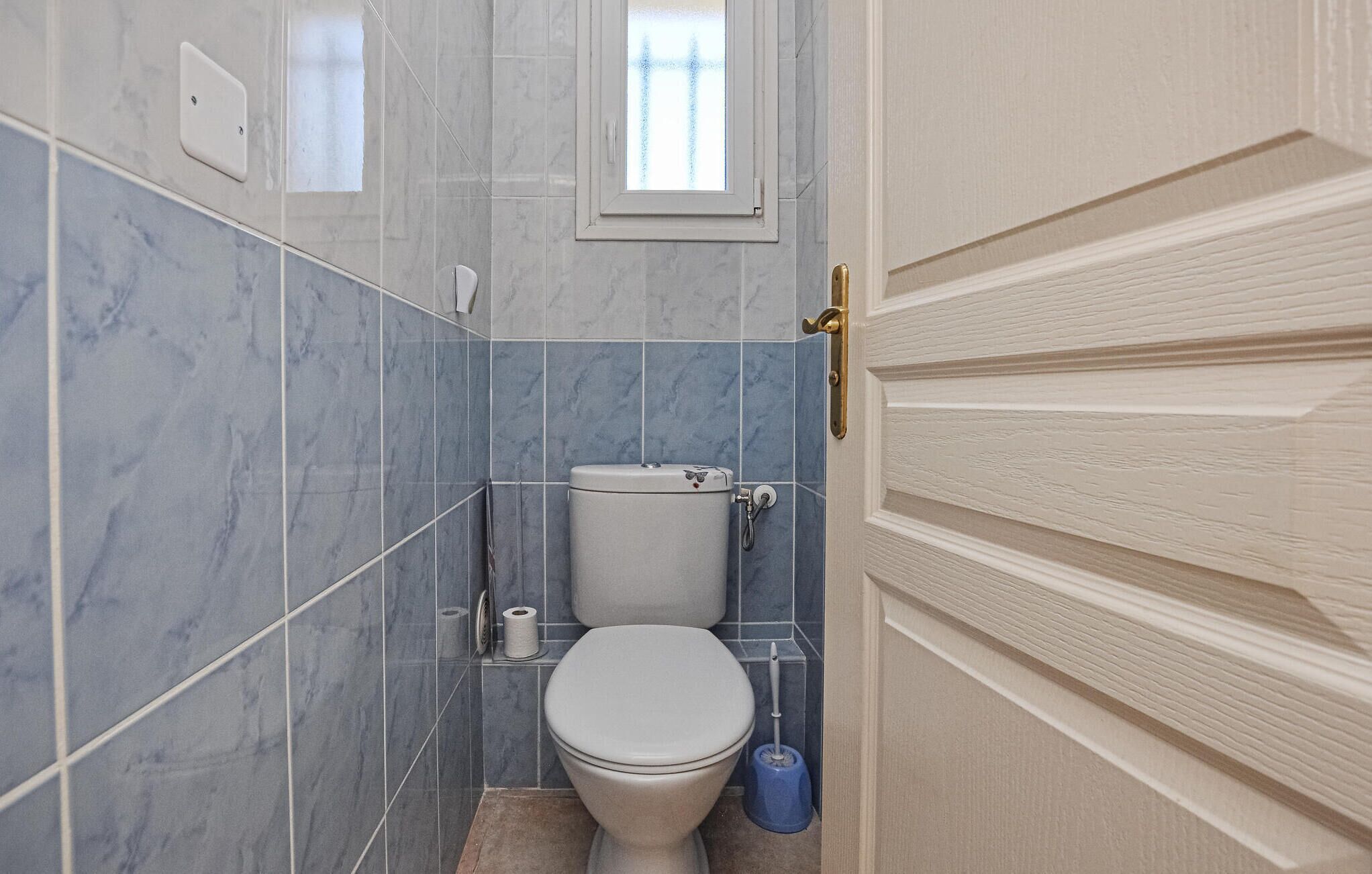 Une salle de bain avec des toilettes, une fenêtre et une porte.