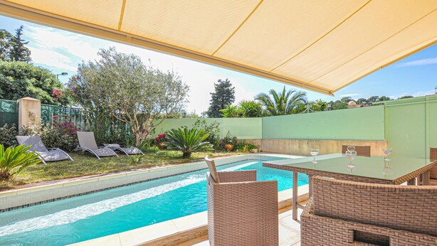 Ein Schwimmbecken mit Liegestühlen und einer überdachten Terrasse.