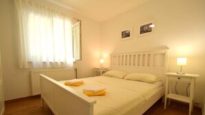 A bedroom with a bed, two bedside tables with lamps, a window with curtains, and a radiator. - Holiday apartment mit Klimaanlage und Meerblick (Čižići)
