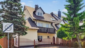 Ein zweistöckiges Haus mit befestigtem Eingang, einem Geschwindigkeitsbegrenzungsschild und blauem Himmel.