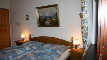 Une chambre à coucher avec un lit en bois, deux lampes de chevet, un tableau au mur et un rideau à motifs floraux.