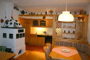A kitchen with wooden cabinets, a dining table with chairs, and a hanging light fixture. - Haus Konradgut - apartment number 13 (St. Lorenzen ob Murau)