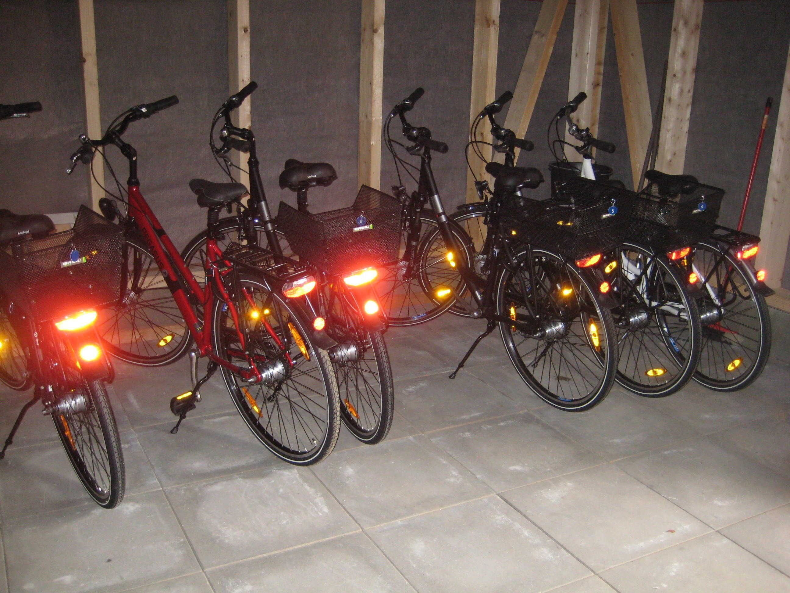 Bicycles parked indoors with lights on.