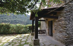 Set amidst a serene mountainous landscape, this charming building features a stone wall, wooden door, and a small courtyard with a metal pole.