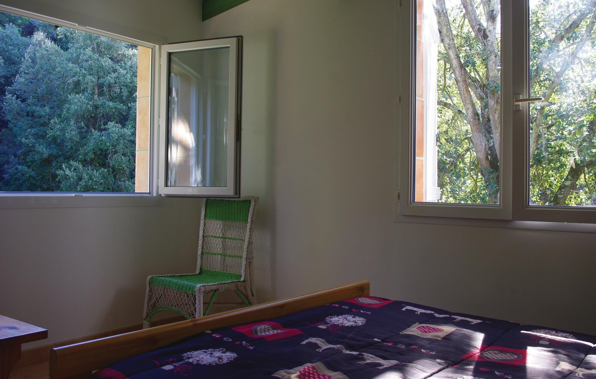 Ein Schlafzimmer mit Bett, Stuhl, Fenster und Spiegel.