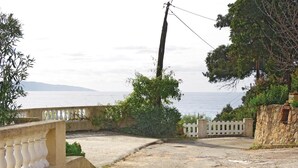 A coastal road with a white fence, a utility pole, and a view of the sea. - Nice apartment in Sagone with kitchen (Sagone)