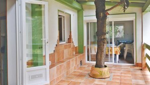 A room with a tiled floor, a large tree in a pot, a staircase, and a door with a glass panel. - Nice apartment in Sagone with kitchen (Sagone)