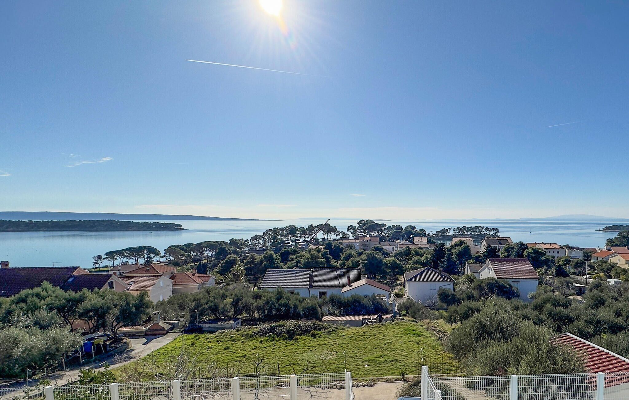 A coastal residential area with houses, a clear sky, and a view of the sea.