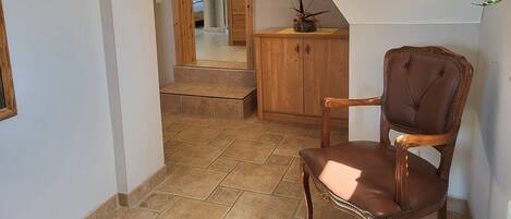 A hallway with a wooden chair, a cabinet, and a staircase leading to another room.