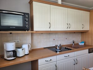 Een keuken met een magnetron, koffiezetapparaat, broodrooster, waterkoker en een fornuis.