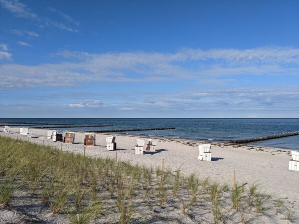 Une plage avec des chaises longues blanches et une structure en bois portant des numéros.