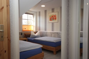 Un dormitorio con dos camas, una ventana con persianas, una lámpara y un cuadro en la pared.