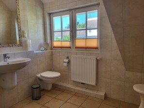 A bathroom with a sink, toilet, window, mirror, and radiator. - House Alex upper floor - House Alex OG (Wustrow)