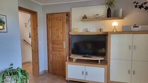 Un salon avec un téléviseur, un meuble en bois et une porte.