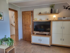 Un salon avec un téléviseur, un meuble en bois et une porte.