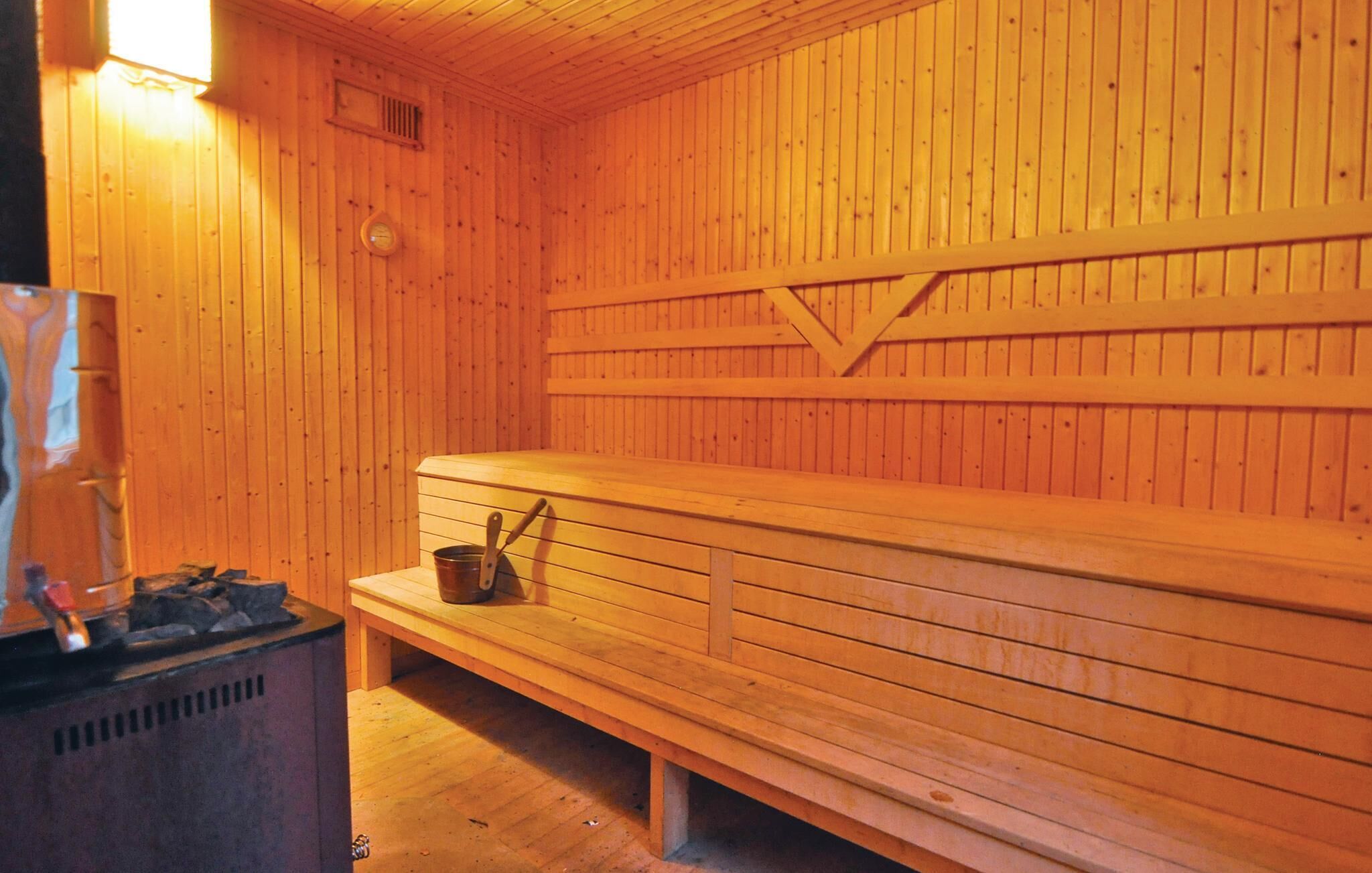 Una sala de sauna con bancos de madera y un asiento con un cubo.