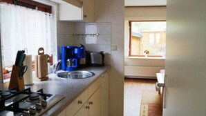 A kitchen with a gas stove, a sink, and a window with a view of the outside.