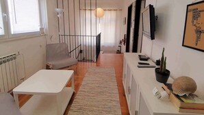 Una sala de estar moderna con un sofá blanco, una mesita, una escalera y una planta en maceta.