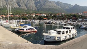 Un puerto deportivo con barcos amarrados, montañas al fondo y un pueblo costero.