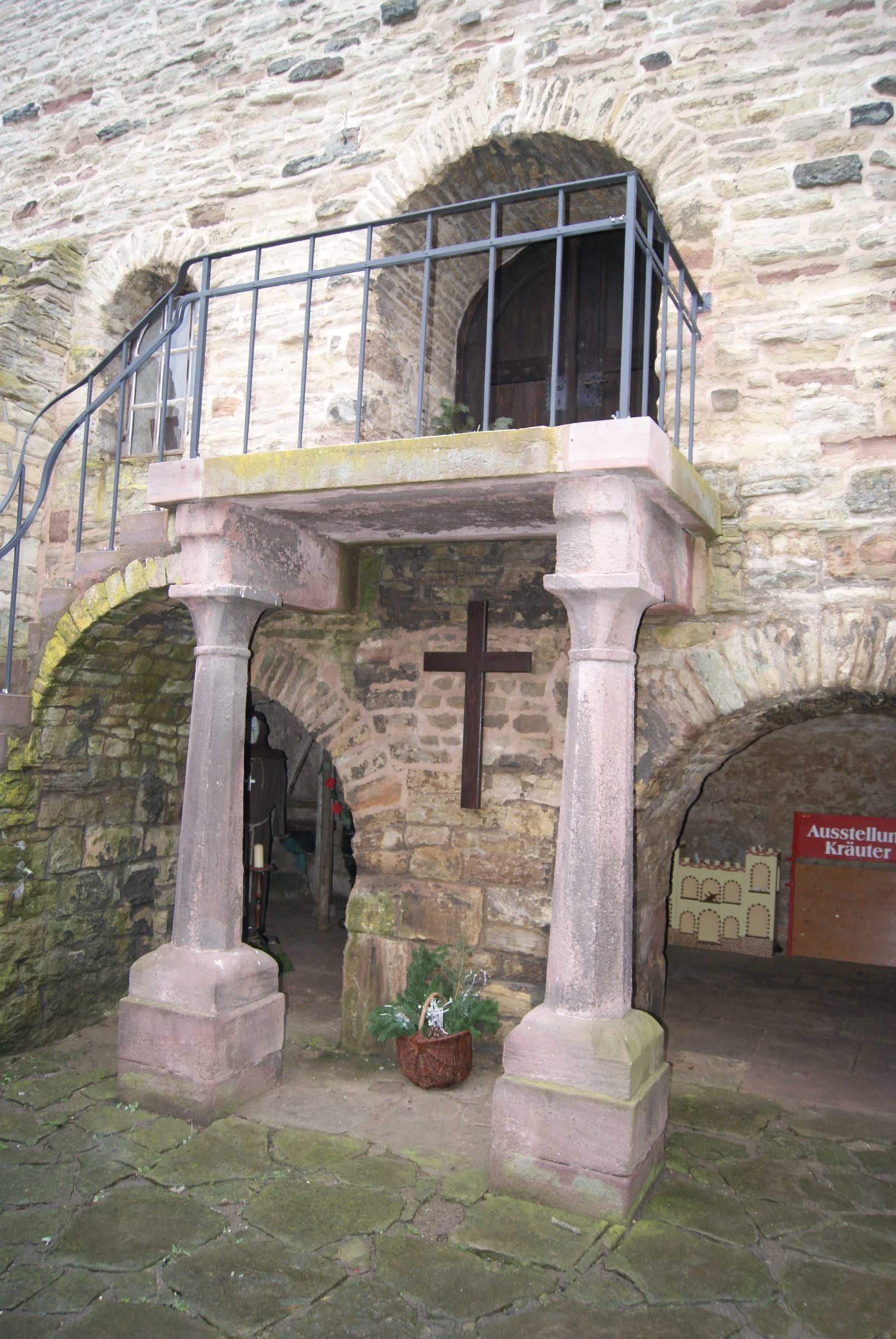 Un bâtiment en pierre doté d’un balcon, de portes en arc de cercle et d’une croix.
