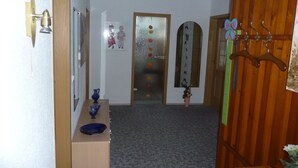A hallway with a wooden door, a mirror, a vase, and a coat rack. - Apartment OG - Apartment / DZ Blesse Allstedt (Allstedt)