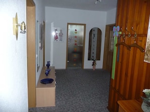 Ein Flur mit Holztür, einem Spiegel, einer Vase mit Blumen und einem Garderobenschrank.