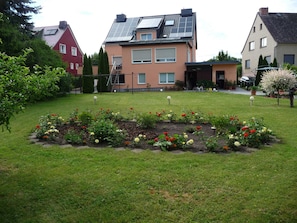 A residential area with a well-maintained garden, solar panels on a house, and a variety of flowering plants. - Apartment OG - Apartment / DZ Blesse Allstedt (Allstedt)