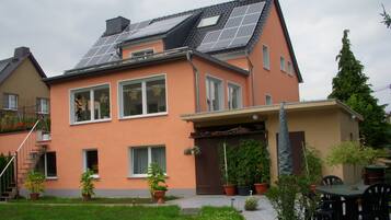 Una casa con paneles solares, un porche cubierto y plantas en macetas.